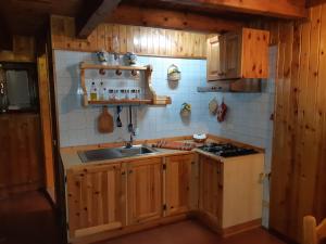 una cucina con armadi in legno, lavandino e piano cottura di Casetta di montagna Viuex a La Magdeleine