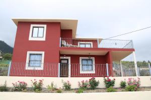 ein rotes Haus mit einem Balkon und Blumen in der Unterkunft Casa Clotilde in Los Llanos de Aridane