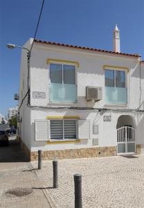 een wit gebouw met ramen aan een straat bij Casa Da Praia "AL" in Monte Gordo