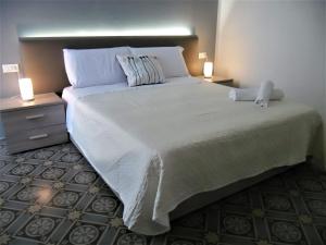 1 dormitorio con 1 cama blanca grande y 2 mesitas de noche en Le vie del Centro, en Palermo