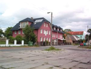 een rood huis met een zwart dak op een straat bij Gościniec ELLA INN Lipniki in Lipniki