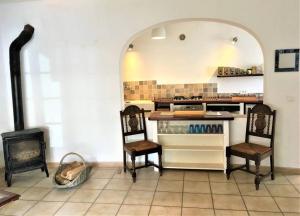 a kitchen with a stove and two chairs in it at La maison Vigne Vierge in Lagrasse