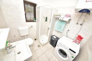 a bathroom with a toilet a sink and a washing machine at Vacation house Nina in Sukošan