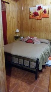 a bedroom with a bed in a wooden wall at Cabañas El Hornero in Puerto Iguazú