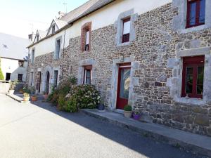 Le Mesnil-Aubert的住宿－Chambres d'hôtes Au Hameau，一座古老的石头建筑,设有红色的门窗