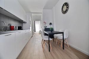 een keuken met een zwarte tafel en witte stoelen bij Rent a Flat - Bruxelles in Brussel