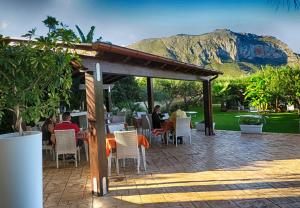 un groupe de personnes assises dans un restaurant avec une montagne en arrière-plan dans l'établissement Trigrana Vacanze Hotel, à Castelluzzo