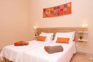 2 bedden in een kamer met witte lakens en oranje kussens bij B&B Syrentum in Sorrento