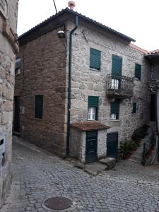 a stone building with green doors and a balcony at Casas da Estrela in Gouveia