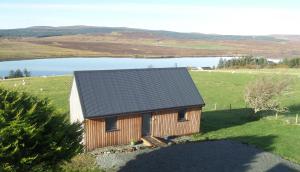 a small wooden house in a field with a lake at Curlew Cottage in Eyre