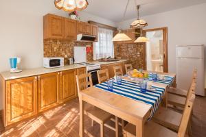 a kitchen with a wooden table and a kitchen with a refrigerator at Villas Marianna in Kalavárda