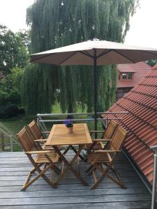 a wooden table and chairs with an umbrella on a deck at Ferienglück Lindwedel in Lindwedel