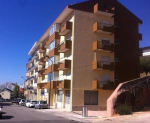 een hoog gebouw met auto's ervoor geparkeerd bij Irís Apartment in Pombal