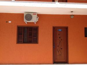 an orange wall with a fan and a door at Chalés Ubatuba 102 - P. Itaguá in Ubatuba