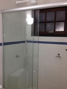 een badkamer met een douche en een glazen deur bij Chalés Ubatuba 102 - P. Itaguá in Ubatuba