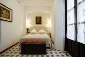 a white bedroom with a bed and a window at Suites Machado in Seville