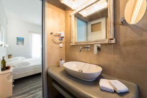 uma casa de banho com um lavatório, um espelho e uma cama em Apartments Tarsa em Drios