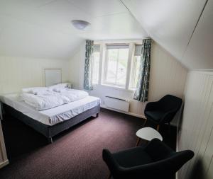 a bedroom with a bed and a chair and a window at Gudvangen Budget Hotel in Gudvangen