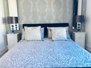 um quarto com uma cama azul e branca com 2 candeeiros em DUNOON - TOWN CENTRE HOLIDAY HOME APARTMENT em Dunoon