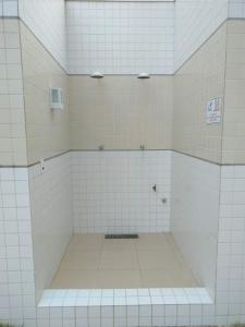 baño con paredes de azulejos blancos y suelo de baldosa. en Apartamento á 2 minutos da Praia, en Praia Grande 29 fotos más