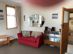 a living room with a red couch and a mirror at Art Deco Apartment #10 sea views, centre of town. in Picton