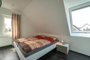 Schlafzimmer mit einem Bett mit roter Bettwäsche und einem Fenster in der Unterkunft Reede Hus Alfonso - Urlaub mit Hund - in Borkum