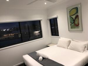 a white bedroom with a bed and a window at Nouveau On Young in Newcastle