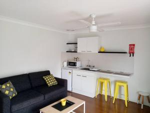 a living room with a couch and a kitchen with yellow stools at The Jervis Bay Villas in Vincentia