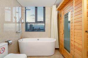 uma banheira branca na casa de banho com uma janela em Luxtery Hotel & Spa em Da Nang