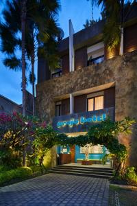 a hotel with a sign on the side of a building at Praja Hotel in Denpasar