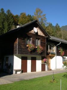una casa de madera con flores en las ventanas en Ferienwohnung Stricker, en Obertraun