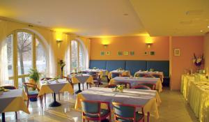 ein Restaurant mit Tischen und Stühlen mit gelben Wänden in der Unterkunft Hotel am Buschkrugpark in Berlin