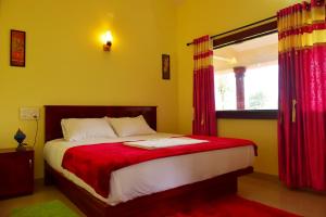 a bedroom with a bed with red curtains and a window at Green Garden Deluxe Room in Vayittiri
