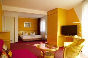 ein Hotelzimmer mit einem Bett und einem TV in der Unterkunft Hotel am Buschkrugpark in Berlin