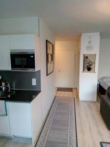 een kleine keuken en een woonkamer met een bank bij Parantolankatu modern one room apartment in Hyvinkää