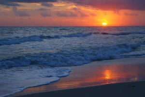 una puesta de sol en la playa con las olas en Plantation Palms en Gulf Shores