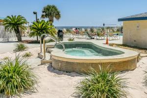 a hot tub in the sand with palm trees at Plantation Palms in Gulf Shores