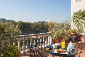 two tables and chairs on a balcony with food at Hotel Lungarno Vespucci 50 in Florence