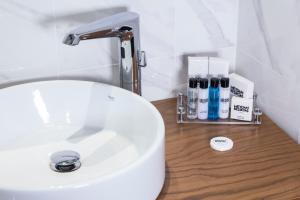 a white bathroom sink with a faucet and some cosmetics at Meydan Besiktas Hotel in Istanbul