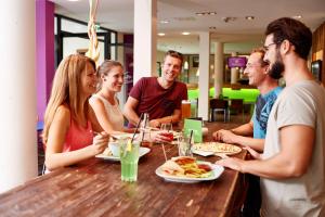 a group of people sitting around a table eating food at Explorer Hotel Kitzbühel in Sankt Johann in Tirol