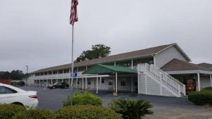 a large building with a flag in a parking lot at Loyalty Inn Hawkinsville in Hawkinsville