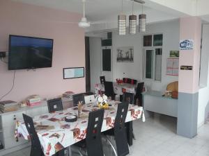 a dining room with a table with chairs and a tv at La Plaine Verte Guesthouse in Port Louis