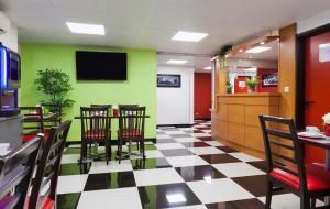 um restaurante com paredes verdes e piso xadrez preto e branco em ENZO HOTELS Chalons en Champagne em Saint-Martin-sur-le-Pré