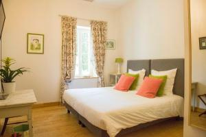Salles-dʼAudeにあるシャトー シャトー ペック-セルイランのベッドルーム1室(オレンジと緑の枕が付いたベッド1台付)