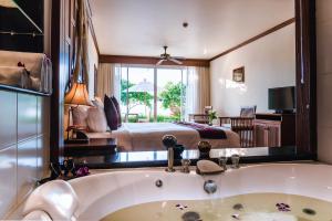ein Badezimmer mit einer Badewanne und ein Schlafzimmer mit einem Bett in der Unterkunft Layalina Hotel in Kamala Beach