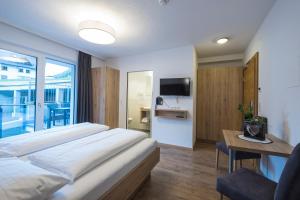 1 dormitorio con 1 cama, escritorio y TV en Chasa Allegria, en Ischgl