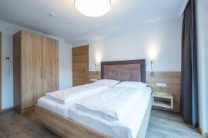 a bedroom with a large white bed with a wooden headboard at Chasa Allegria in Ischgl