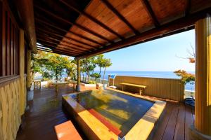 a hot tub on a deck with a view of the ocean at Seaside Hotel Mimatsu Ooetei in Beppu