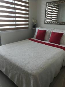 a bedroom with a large white bed with red pillows at Sea Residences Holiday Rentals in Manila