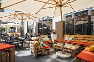 a patio area with tables, chairs and umbrellas at INNSiDE by Meliá Frankfurt Ostend in Frankfurt